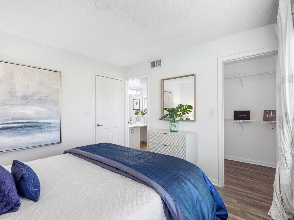 A bedroom with a large bed and a painting on the wall.